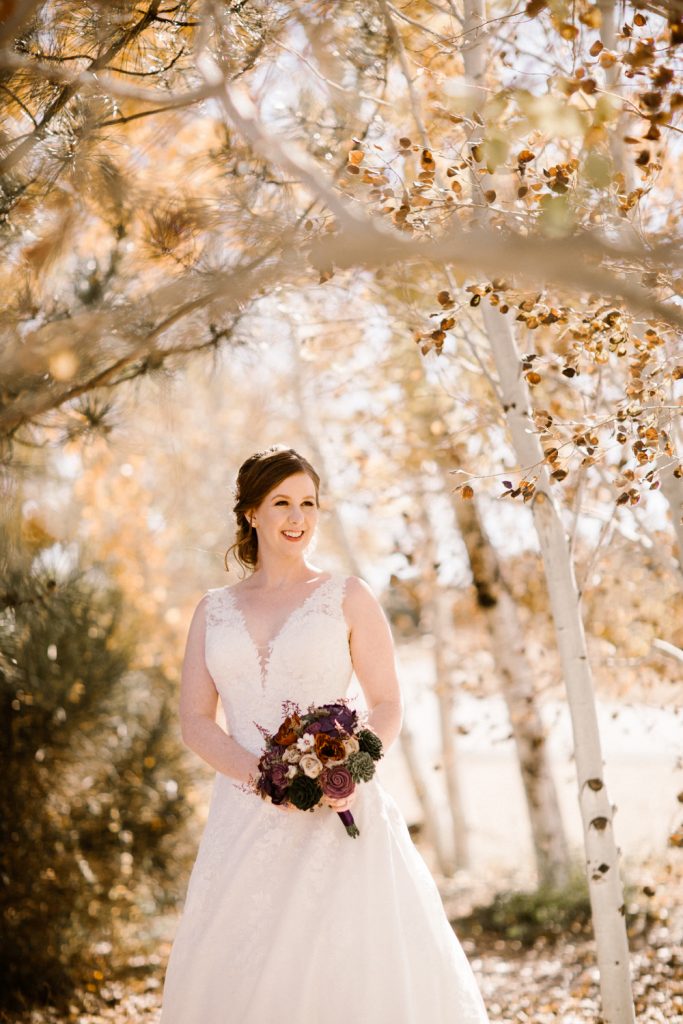 Bride posing with bouquet under trees