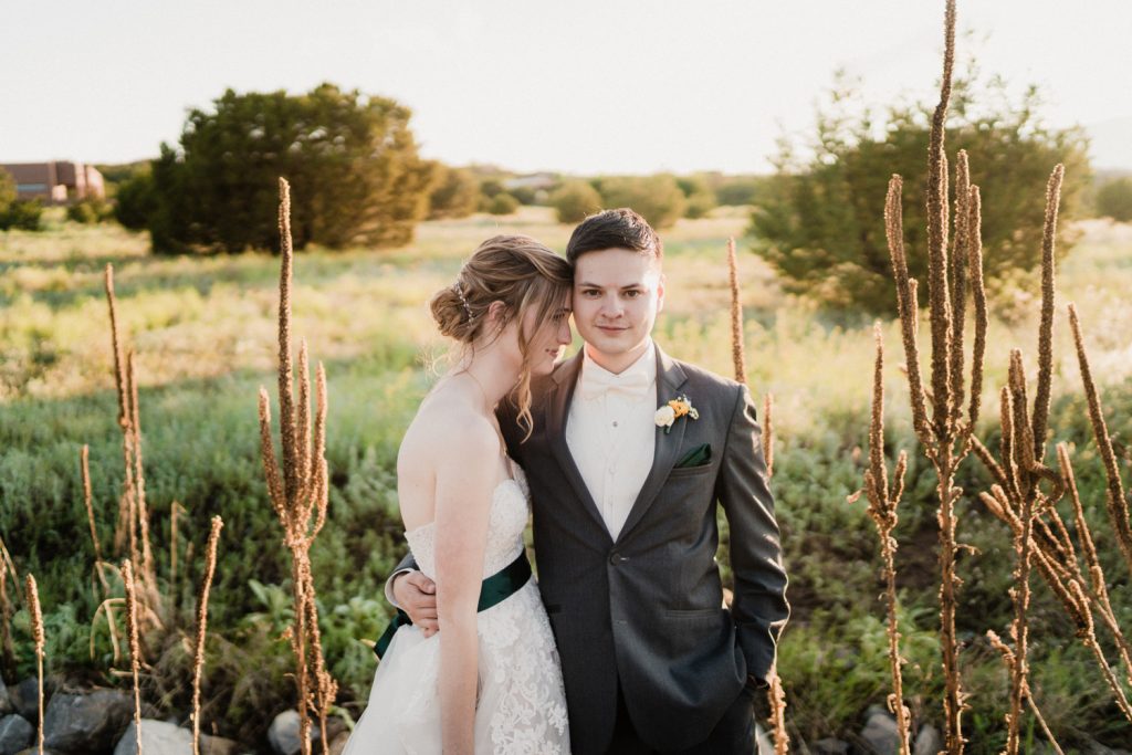 Bride and groom posing in field of plants and flowers